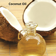 An open coconut in 2 halves and a glass decanter full of liquid coconut oil